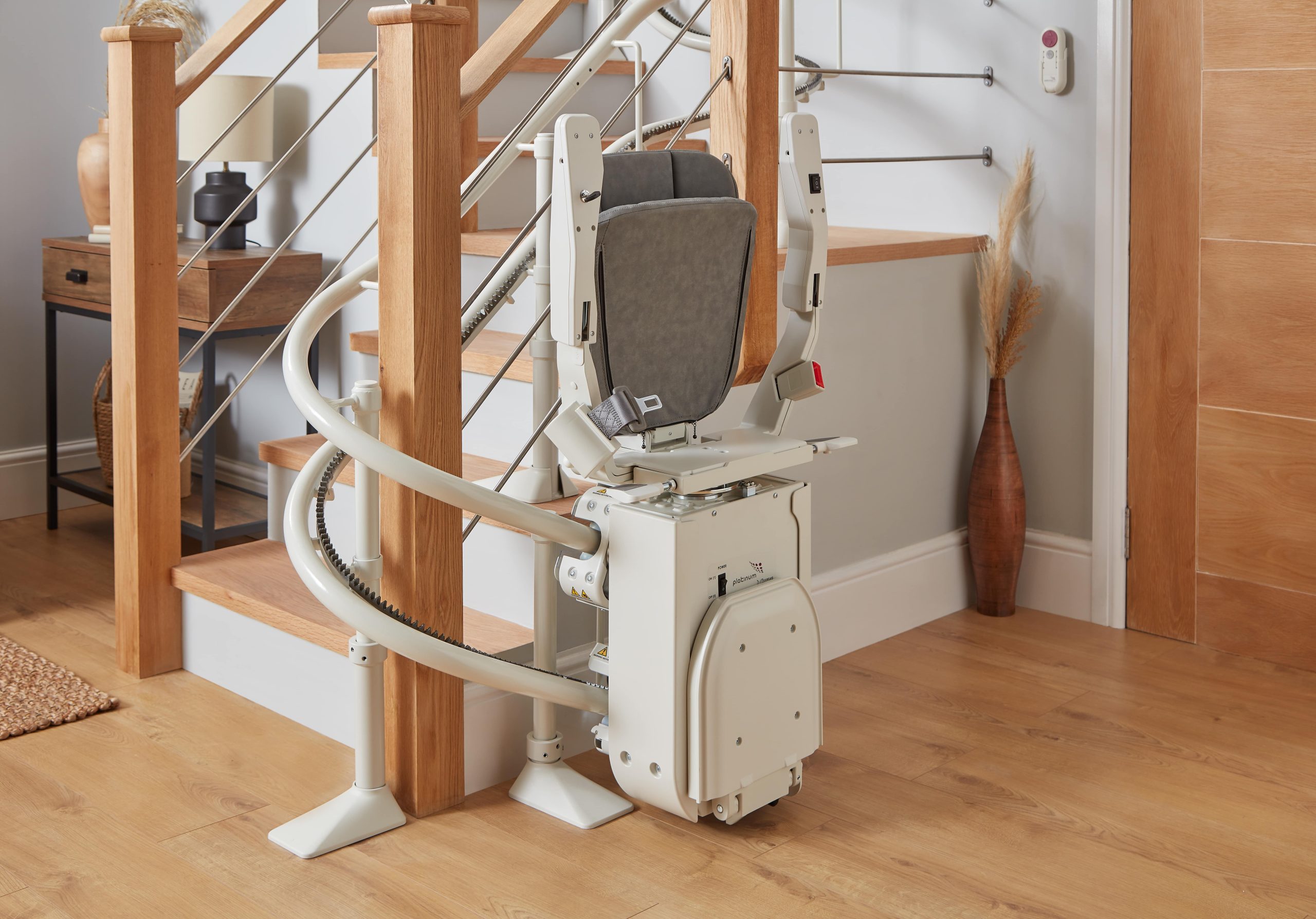 Platinum Ergo Curve curved stairlift twin rail seat folded parked at bottom of staircase