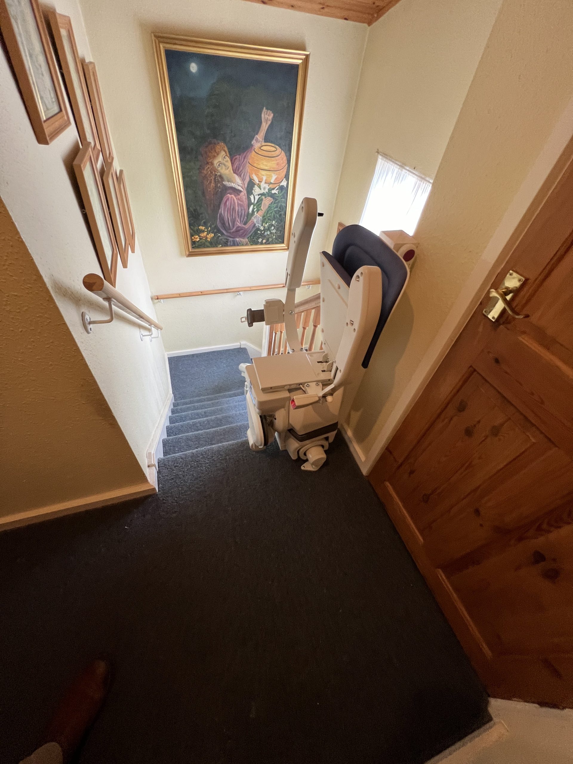 Platinum Ergo Ultimate curved stairlift specialist example parked with seat and arms folded at top of staircase
